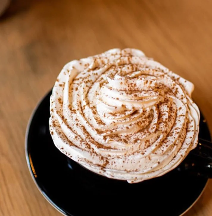 Bebida caliente con crema y canela en taza negra